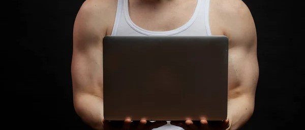 hombre culturista con grandes brazos escribiendo en el ordenador 
