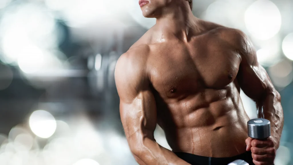 cuerpo musculado con el torso al descubierto y agarrando una mancuerna con la mano izquierda