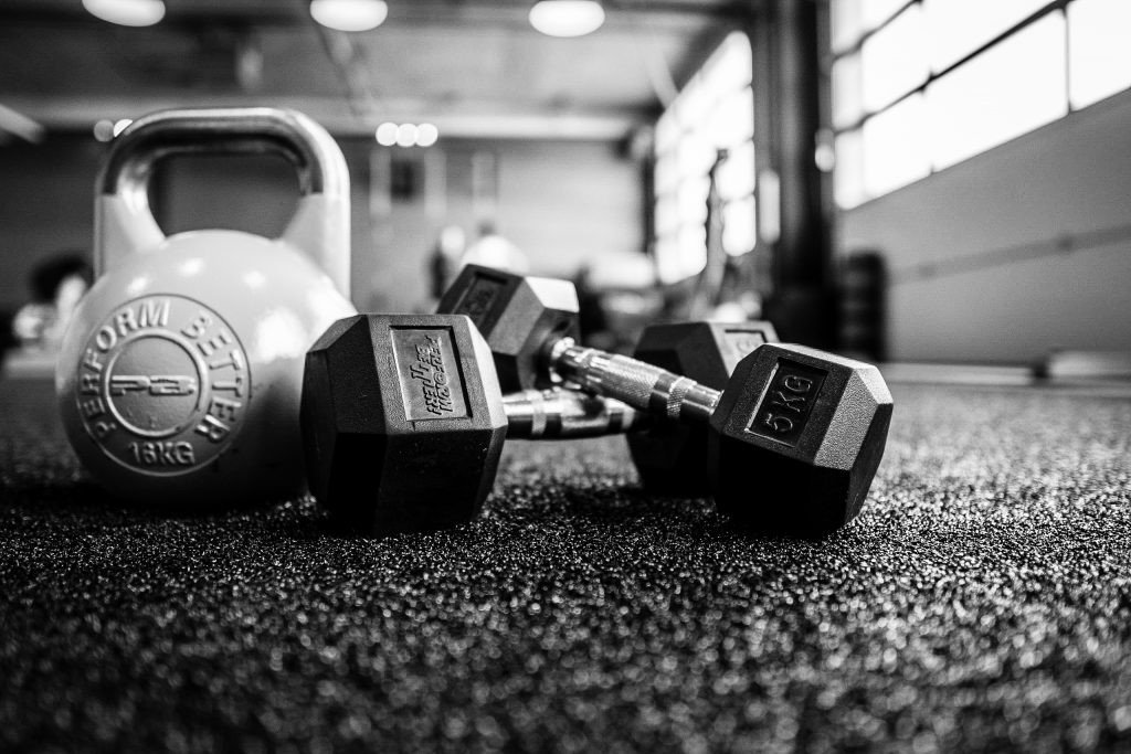 mancuernas y pesas en primer plano y de fondo parte del gimnasio