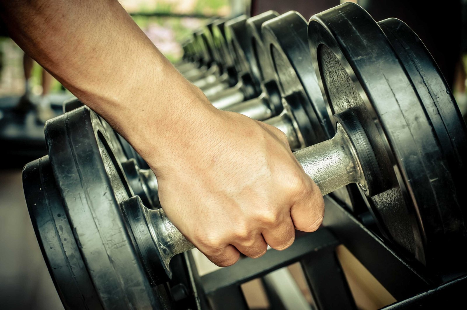 usuario de gimnasio coge una mancuerna con su mano derecha