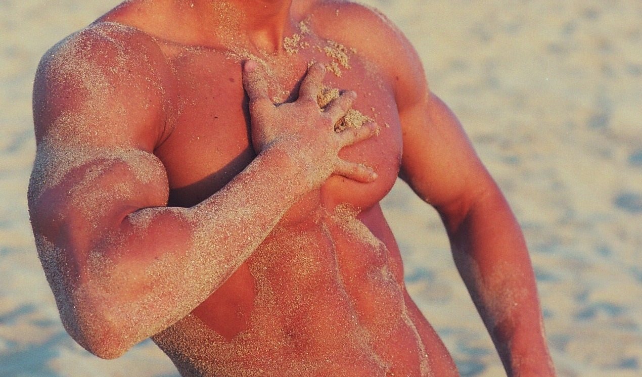 Cuerpo masculino bronceado posando en una playa