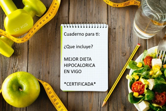 Vegetales variados, manzanas, un vaso de agua y una cinta métrica alrededor de libreta que lleva escrito "cuaderno para ti ¿Qué incluye? mejor dieta hipocalórica en Vigo certificada"