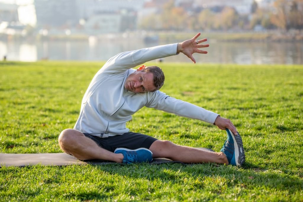 deportista hace estiramientos sentado en el suelo y al aire libre