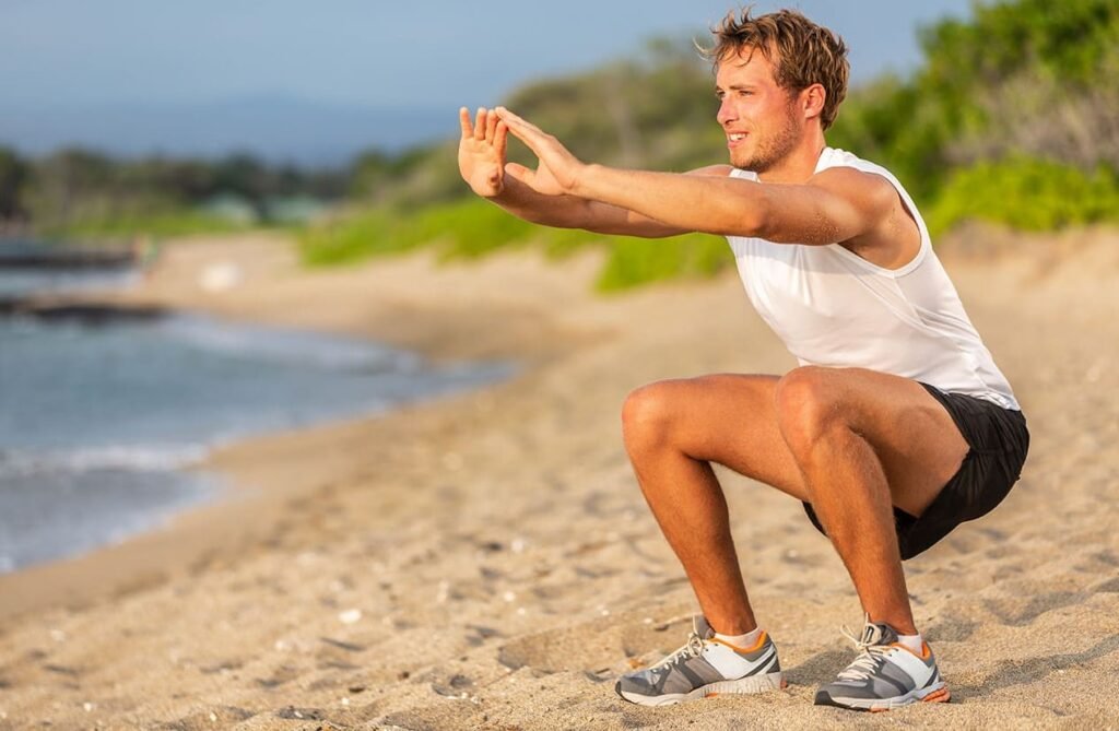 deportista hace sentadillas con el peso de su propio cuerpo en la playa