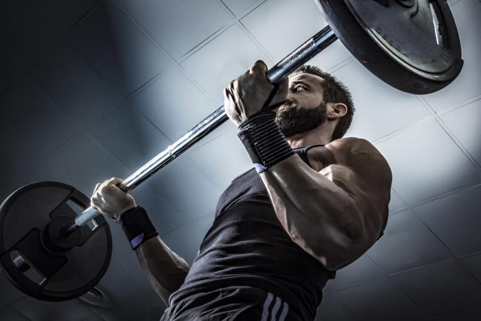 hombre levantando una barra con peso en curl de biceps
