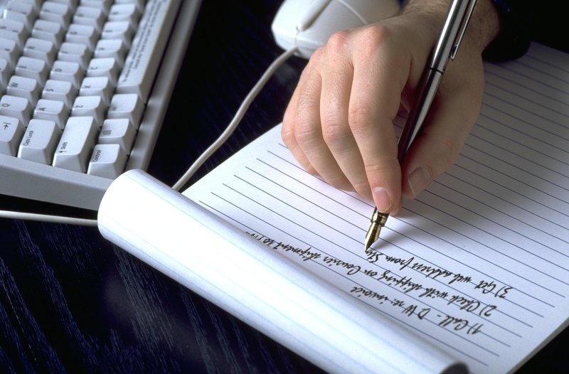 mano escribe en un blog y un teclado de ordenador portátil