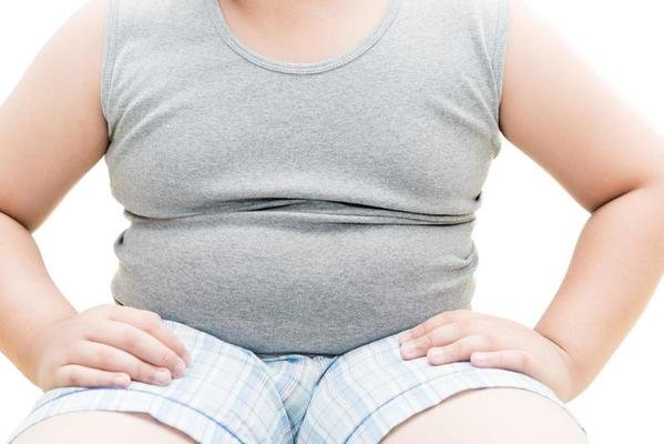 hombre obeso de camiseta gris y pantalón corto blanco sentado y con las manos apoyadas sobre sus piernas