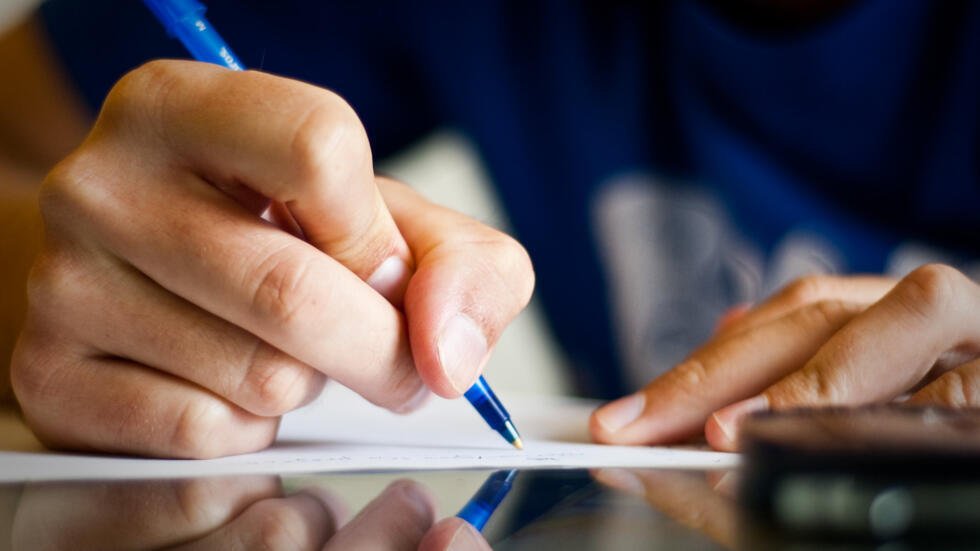 mano derecha escribiendo con bolígrafo azul una note en un papel