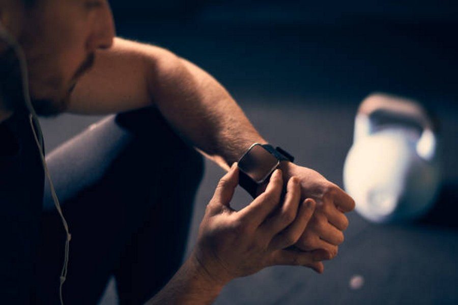 hombre sentado visualiza la hora a partir de su reloj situado en su mano izquierda