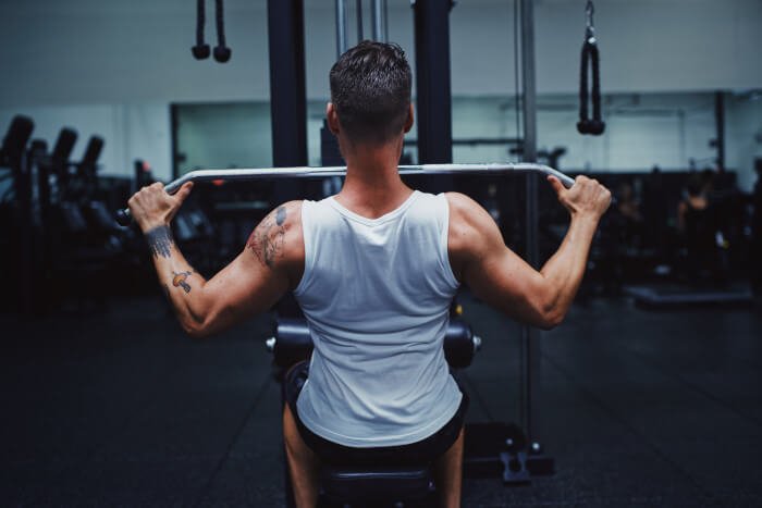 cliente de gimnasio realiza una repetición de jalón al pecho en maquina