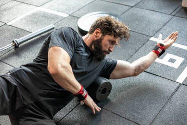hombre en el gimnasio tumbado de manera lateral sobre el suelo