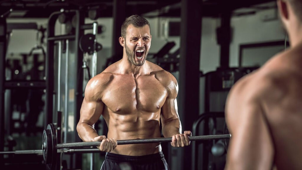 hombre mayor de 40m años sin camiseta y un buen look se esfuerza durante una serie de curl bíceps barra